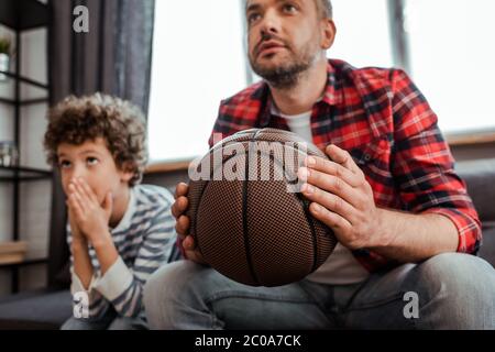 objectif sélectif du père qui tient le basket-ball tout en regardant le championnat avec son fils Banque D'Images