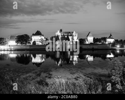 Château de Malbork la nuit avec réflexion dans la rivière Nogat, Pologne. Image en noir et blanc. Banque D'Images