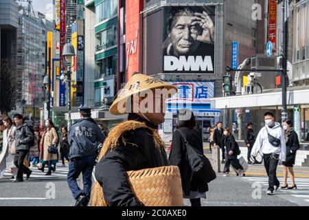 Un jeune homme portant des vêtements traditionaljaponais et chapeau conique au populaire ShibuyaSchambleCrossing.Buildings avec des annonces dans le fond Banque D'Images
