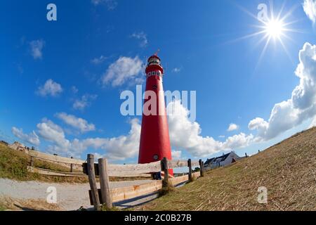 soleil et tour rouge de phare sur la côte Banque D'Images