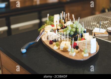 Planche en bois avec tranches de différents types de fromage mûri servi avec des olives, des raisins, des fraises et des framboises. Fête, fête Banque D'Images