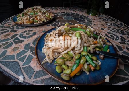 Un plat de nouilles végétaliennes avec des légumes comme la carotte, les haricots verts et l'edamame. Banque D'Images