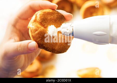 remplir la pâte de profiterolle de crème à l'aide du sachet de pâtisserie de préparation faite maison Banque D'Images