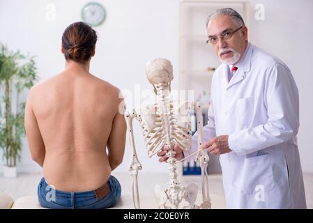 Jeune homme blessé au dos, rendant visite à un médecin expérimenté Banque D'Images