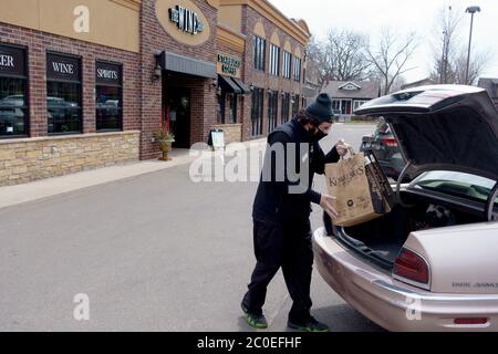 Homme plaçant des provisions commandées dans le coffre de voiture du marché de Kowalski en gardant socialement distance en portant un masque. St Paul Minnesota MN États-Unis Banque D'Images