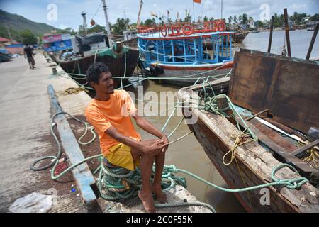 URAN, Inde. 11 juin 2020. Un pêcheur est assis près de son bateau stationné à la jetée de Karanja à Ouran.la pêche n'est pas autorisée pendant la saison des pluies, les pêcheurs tirent leurs bateaux vers la rive pour l'entretien et les réparations avant de s'aventurer à nouveau après la mousson est terminée. Crédit : SOPA Images Limited/Alamy Live News Banque D'Images