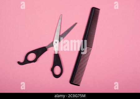 ciseaux et peigne sur fond rose, outils de coiffeur. Banque D'Images