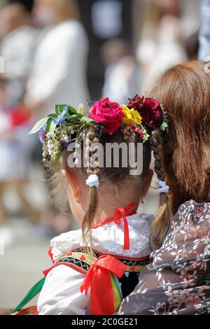 Mère tient sa petite fille en costume folklorique traditionnel de Cracovie en Pologne et belle couronne fleurie sur sa tête. Banque D'Images