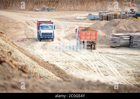 Deux tombereaux pour mines lourdes de plusieurs tonnes sont vides et chargés pendant l'enlèvement du sol de construction du chantier. Concept de transport Banque D'Images