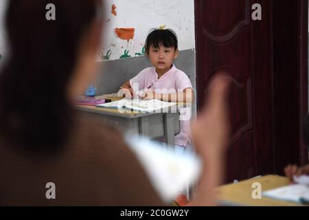 (200612) -- HEFEI, 12 juin 2020 (Xinhua) -- Chu Siyang prend une classe dans le village de Wangli, dans le comté de Yingshang, dans la province d'Anhui, en Chine orientale, le 10 juin 2020. Chu Siyang est une jeune fille de 9 ans, dont les parents sont tous deux des travailleurs de base engagés dans la lutte contre la pauvreté dans le pays. En 2017, le père de Siyang, Zheng Jiawei, s'est porté volontaire pour travailler comme travailleur de base dans le village de Wangli, dans le comté de Yingshang, en aidant les villageois locaux à éliminer la pauvreté et à développer des infrastructures. Sa mère, déjà occupée à travailler en première ligne dans des villages frappés par la pauvreté, ne pouvait pas se permettre de prendre soin de Siyang. Banque D'Images