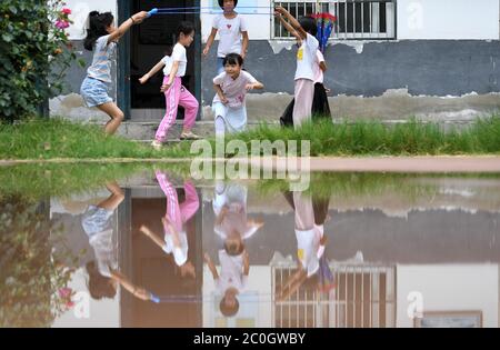 (200612) -- HEFEI, 12 juin 2020 (Xinhua) -- Chu Siyang (3e L, devant) joue avec ses camarades de classe lors d'une pause dans le village de Wangli du comté de Yingshang, province d'Anhui en Chine orientale, le 10 juin 2020. Chu Siyang est une jeune fille de 9 ans, dont les parents sont tous deux des travailleurs de base engagés dans la lutte contre la pauvreté dans le pays. En 2017, le père de Siyang, Zheng Jiawei, s'est porté volontaire pour travailler comme travailleur de base dans le village de Wangli, dans le comté de Yingshang, en aidant les villageois locaux à éliminer la pauvreté et à développer des infrastructures. Sa mère, déjà occupée à travailler à la ligne de front des villages frappés par la pauvreté, co Banque D'Images