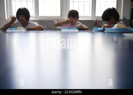 (200612) -- HEFEI, 12 juin 2020 (Xinhua) -- Chu Siyang (C) a déjeuné avec ses camarades de classe dans le village de Wangli, dans le comté de Yingshang, dans la province d'Anhui, en Chine orientale, le 10 juin 2020. Chu Siyang est une jeune fille de 9 ans, dont les parents sont tous deux des travailleurs de base engagés dans la lutte contre la pauvreté dans le pays. En 2017, le père de Siyang, Zheng Jiawei, s'est porté volontaire pour travailler comme travailleur de base dans le village de Wangli, dans le comté de Yingshang, en aidant les villageois locaux à éliminer la pauvreté et à développer des infrastructures. Sa mère, déjà occupée à travailler en première ligne dans les villages frappés par la pauvreté, ne pouvait pas lui permettre de se consacrer de temps Banque D'Images