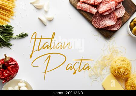 Vue de dessus d'un plat de viande, pâtes et ingrédients sur fond blanc, illustration des pâtes italiennes Banque D'Images