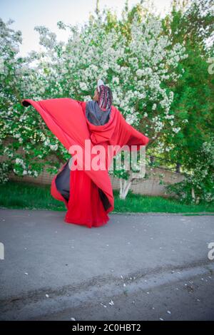 Reine dans la couronne et le manteau royal. Jolie fille sur le fond d'un jardin fleuri. Afro-américain en rouge Banque D'Images