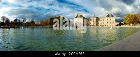 Vue panoramique sur la fontaine du jardin de Luxembourg dans une lumière automnale chaude et un ciel bleu avec quelques petits bateaux en bois Banque D'Images