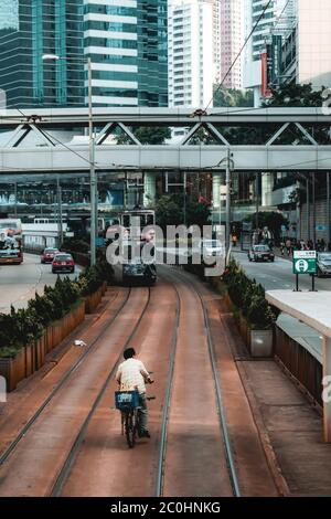 Homme ivre sur un vélo sur les voies de tram à Hong Kong Chine Banque D'Images