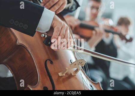 Violoncelle professionnel mains du joueur de près, il est l'exécution de la section de chaîne avec l'orchestre symphonique Banque D'Images