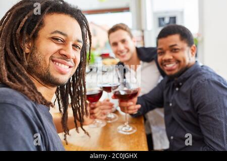 Des hommes heureux comme amis qui boivent du vin ensemble dans la cuisine Banque D'Images