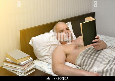 Un jeune homme, un samedi matin, lit un livre dans sa chambre. Auto-isolation. Banque D'Images