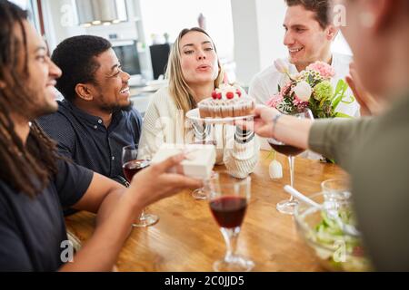 Une femme fête son anniversaire avec des amis et un gâteau et souffle la bougie Banque D'Images