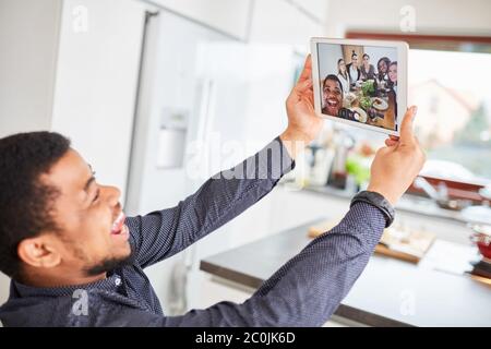 Homme africain faisant le selfie par groupe en utilisant un ordinateur tablette au repas à la table de salle à manger Banque D'Images