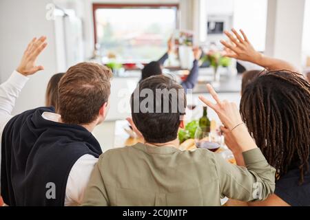 Amis à la table mangeant des signaux de main et des salutations pour un appel vidéo ou selfie Banque D'Images