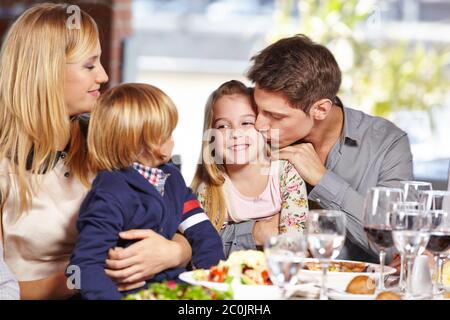 Le père embrasse sa fille au restaurant au déjeuner et sa mère et son fils regardent Banque D'Images