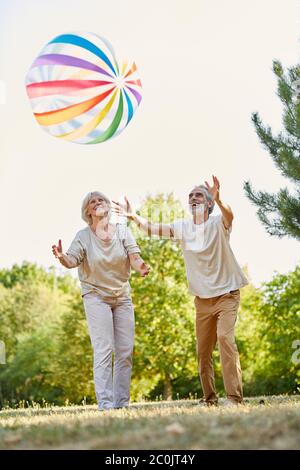 Deux personnes âgées jouent avec une balle colorée en été dans la nature Banque D'Images