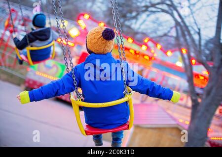 Enfant, mignon garçon chaîne d'équitation carrousel swing sur le coucher du soleil, mouvement flou, arrière-plan coloré Banque D'Images