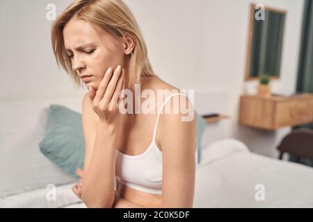 Jeune femme blonde dépressive ayant un mal de dents Banque D'Images