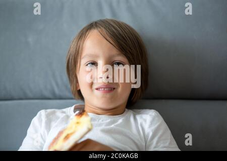 Une petite pizza de race blanche. Enfant affamé prenant un morceau de pizza lors d'une fête de pizza. Enfant taché Banque D'Images