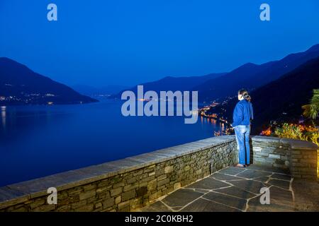 Femme Profitez d'une vue panoramique sur le lac majeur alpin avec la montagne à l'heure bleue au Tessin, Suisse. Banque D'Images