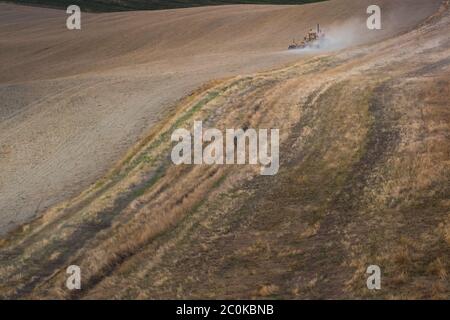 Lajatico, paysage vallonné au coucher du soleil avec un tracteur en travail à côté du célèbre Teatro del Silenzio par Andrea Bocelli. Pise, Toscane, Italie Banque D'Images