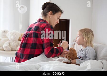 Mère et bébé tôt le matin, maman s'occupe de son enfant malade. Bébé au lit avec fièvre et nez courant Banque D'Images