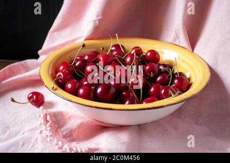 Cerises fraîches dans un bol en céramique jaune sur la table. Récolte estivale. De délicieuses baies rouges. Gros plan. Aliments crus. Banque D'Images