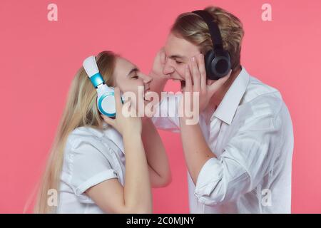 guy et fille dans un casque. écoutez de la musique tout en exprimant des émotions avec un baiser. dos rose Banque D'Images