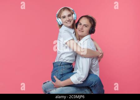 guy et fille dans un casque. écoutez de la musique tout en exprimant des émotions avec un baiser. dos rose Banque D'Images