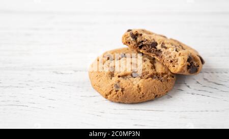 Biscuit aux pépites de chocolat. Deux biscuits avec des gouttes de chocolat sur une table en bois blanc. Place pour le message. Isolé Banque D'Images