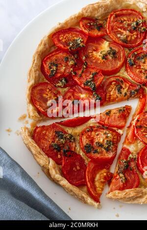 Tarte aux tomates et à la moutarde avec tranche coupée sur une grande assiette blanche Banque D'Images