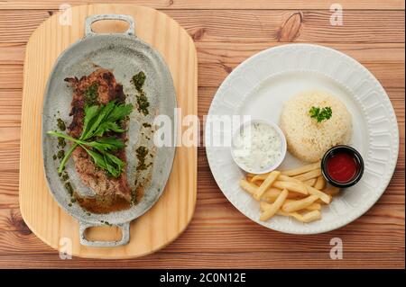 Faire cuire au barbecue la viande avec du riz et des frites sur des assiettes dans une table en bois Banque D'Images