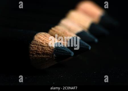 Un groupe de crayons est conservé sur un papier foncé dans l'ordre croissant. Concept d'éducation. Mise au point sélective sur la pointe du crayon proximal Banque D'Images