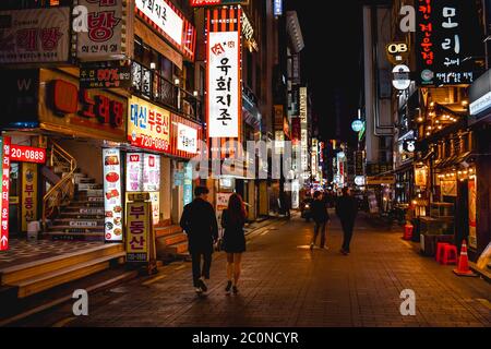 Couple marchant dans le quartier néons lumineux de Myeongdong Séoul en Corée Banque D'Images