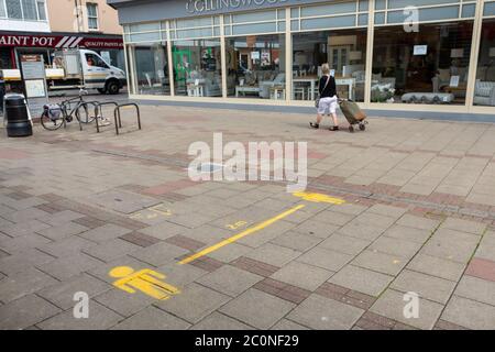 Worthing, Royaume-Uni, 12 juin 2020. Un message d'avertissement jaune COVID-19 à 2 mètres d'intervalle peint sur la rue à l'extérieur des boutiques. Le message a été peint pour rappeler aux acheteurs de se tenir à distance socialement une fois que les magasins ont rouvert pendant la crise pandémique du coronavirus COVID-19. Crédit : Scott Ramsey/Alay Live News. Banque D'Images