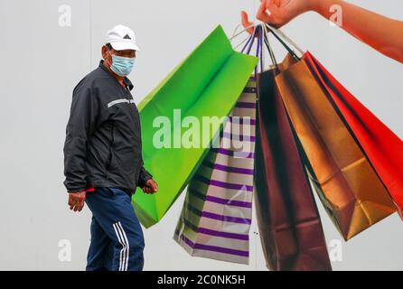 Winchester, Hampshire. 12 juin 2020. Les boutiques de Winchester se préparent à rouvrir le lundi 15 après le blocage du coronavirus. Un homme dans un masque facial passe devant une affiche de shopping sur une unité de shopping à bord dans la High Street. Credit Stuart Martin/ Alay Live News Banque D'Images