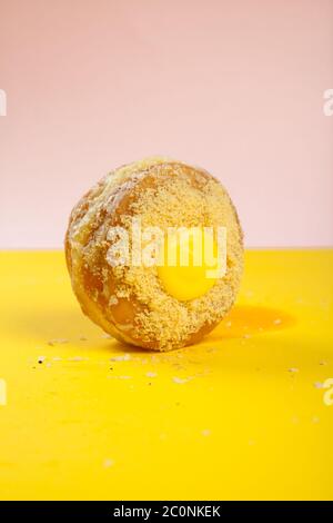 Beignet de crème anglaise au citron sur fond jaune et rose vif et coloré Banque D'Images