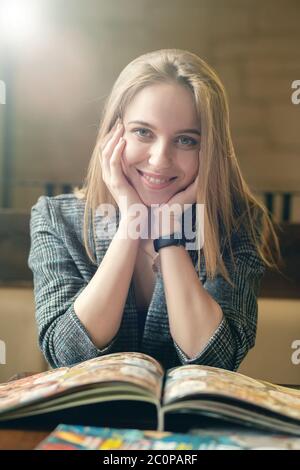 bonne jeune femme avec un magazine regardant l'appareil photo, souriant Banque D'Images