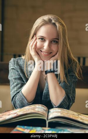 bonne jeune femme avec un magazine regardant l'appareil photo, souriant Banque D'Images