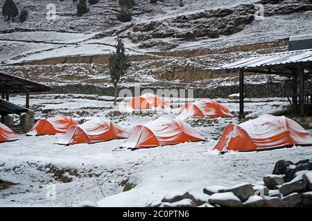 Camping en hiver, tentes orange couvertes de neige. Sakteng, Bhoutan oriental Banque D'Images