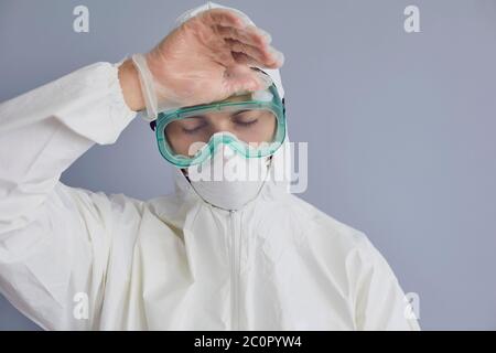 Médecin fatigué portant un costume de noisette sur fond gris. Spécialiste médical épuisé en raison d'une pandémie de maladie infectieuse Banque D'Images