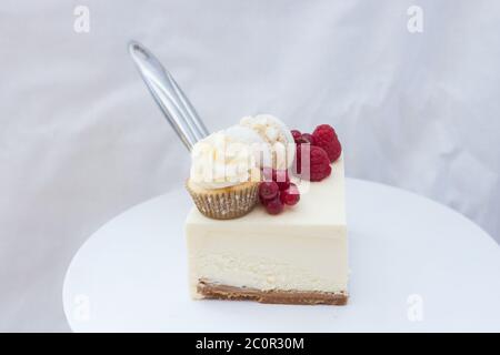 Tranche de cheesecake à la vanille classique New York avec framboise fraîche et cassis sur cakestan blanc. Banque D'Images